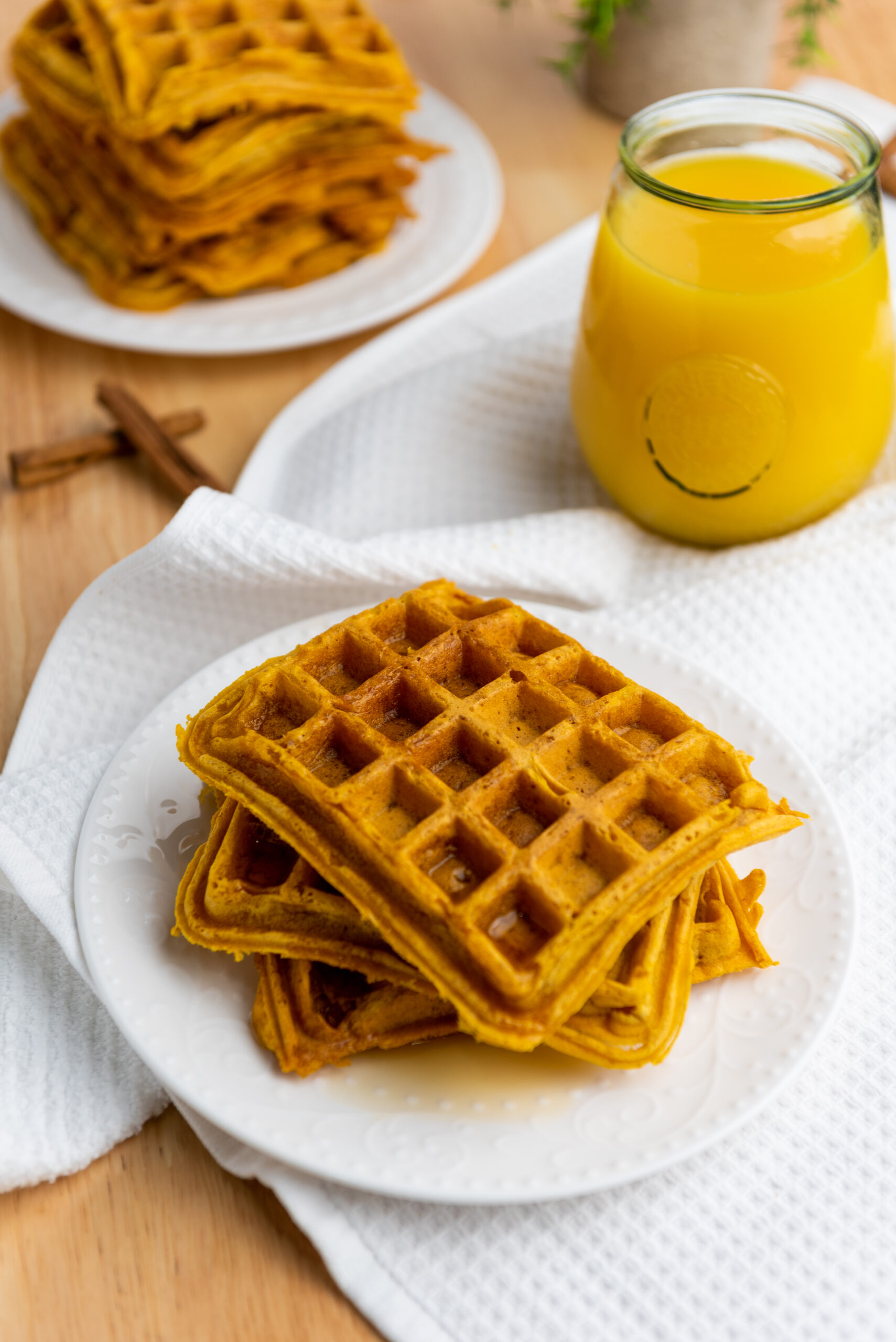 A plate of vegan pumpkin spice waffles and a drink.