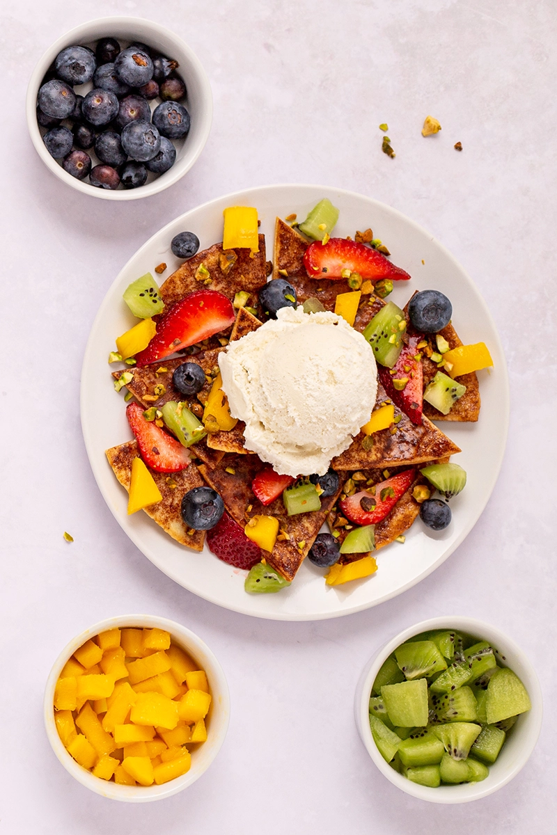 A plate with fruit and ice cream, resembling fruit nachos.