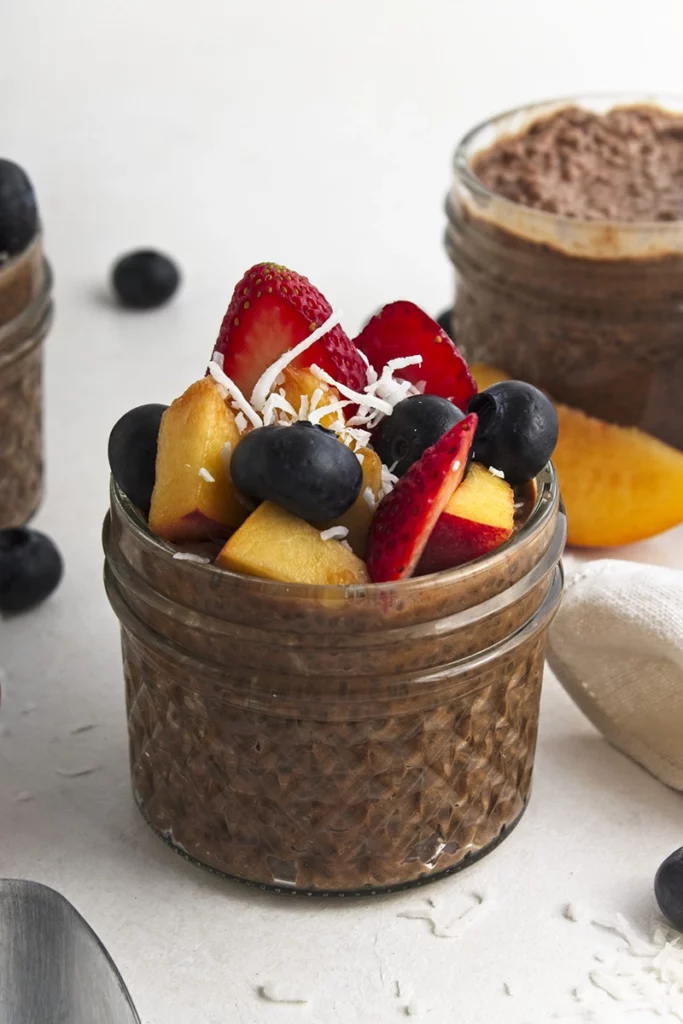 Chocolate chia pudding in a jar with blueberries and strawberries.