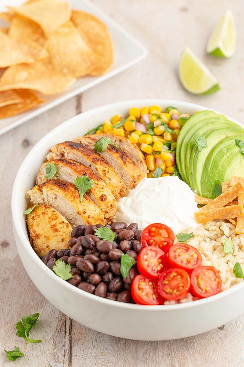 Southwest chicken rice bowl with sour cream and tortilla chips.