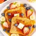 A plate of French toast with berries and butter, perfect for one person.