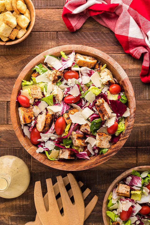 Exciting chicken salad in wooden bowls on a rustic wooden table.