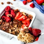 A single serve bowl of baked oats with berries and pecans.