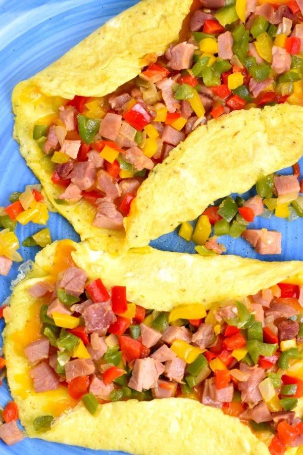 Two protein-packed omelets with ham and peppers on a blue plate.