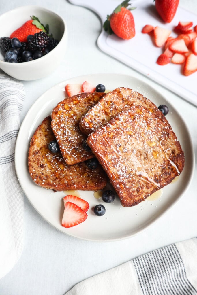 A plate of high-protein french toast topped with berries and powdered sugar.