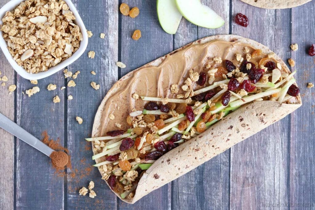 A college commuter lunch idea - a burrito with granola and cranberries on a wooden table.