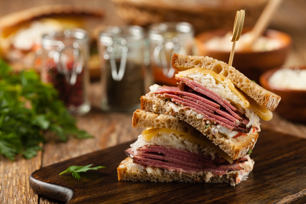 A delicious college commuter lunch idea - a flavorful sandwich with meat displayed on a rustic wooden cutting board.