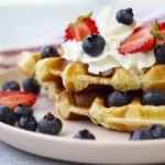 Waffles topped with berries and whipped cream.