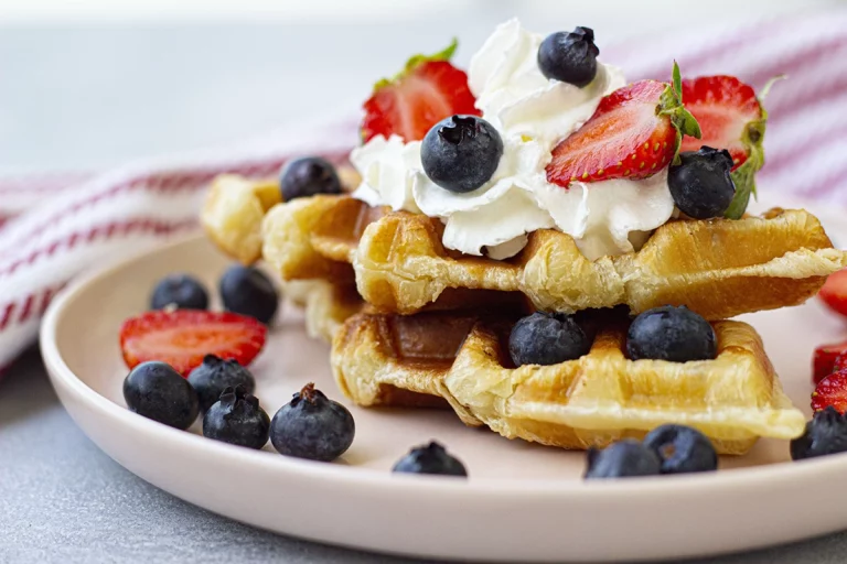 Waffles topped with berries and whipped cream.