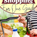 A person is holding a red basket filled with groceries—including a bottle of milk, lettuce, and paper bags—perfectly capturing the essentials of grocery shopping for one. Text reads “Grocery Shopping For One Guide.”.
